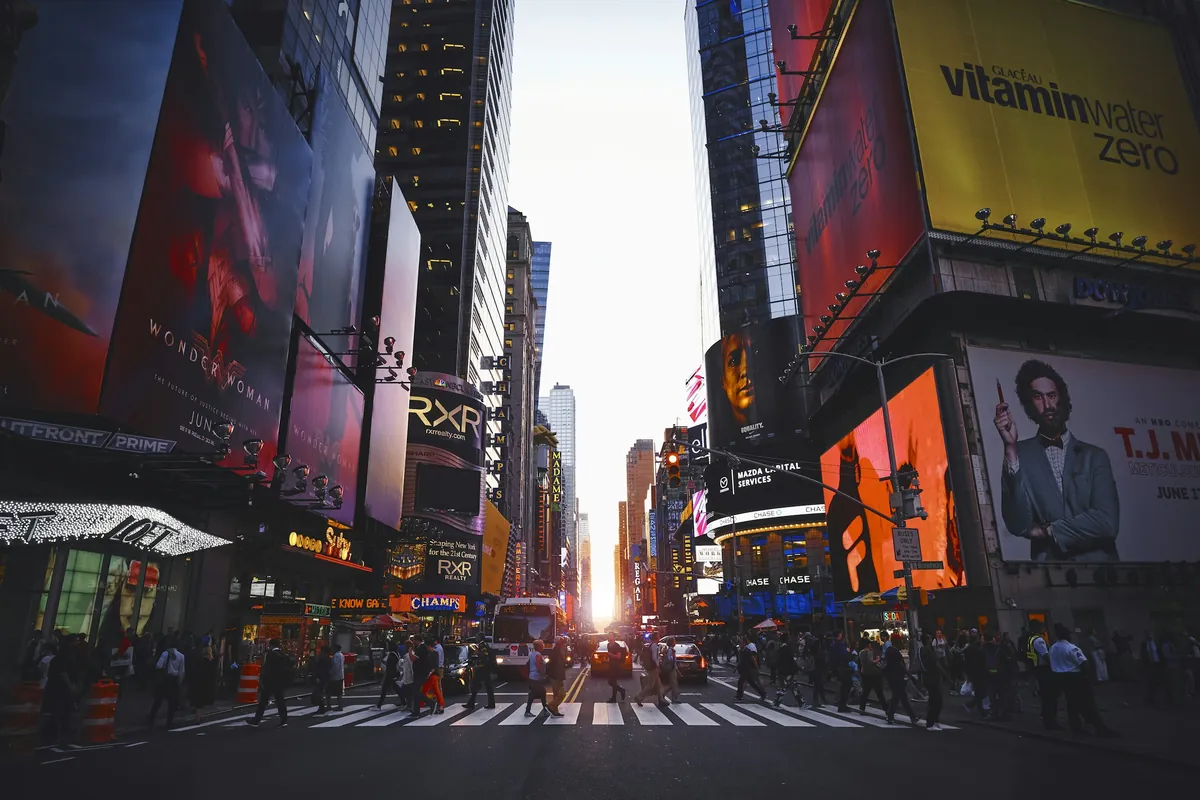Times Square in Manhattan at dusk with neon signs and yellow taxis